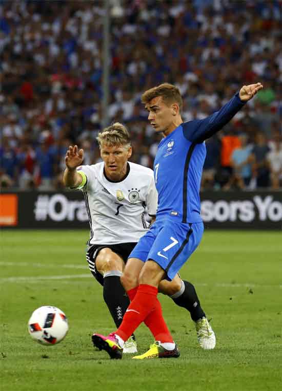 Griezmann disputa un balón con Bastian Schweinsteiger