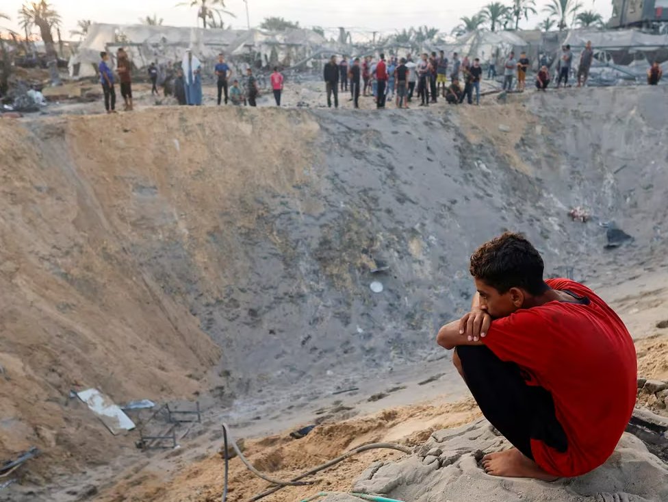 Un niño palestino observa el cráter dejado por los ataques israelíes contra un campamento de tiendas de Al Mawasi