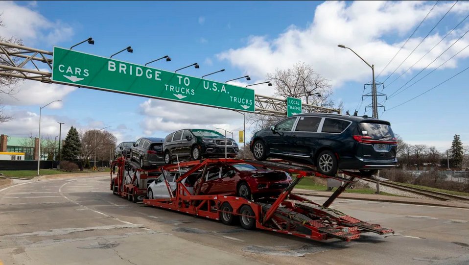 Un camión con vehículos se dispone a cruzar el puente Ambassador desde Canadá a Estados Unidos.