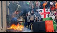 Manifestantes lanzan un contenedor de basura en llamas frente a un hotel