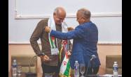 El embajador saharauí en Cuba, Omar Bulsan, coloca la banda con las banderas de la RASD y Cuba a Ricardo Ronquillo, presidente de la UPEC.