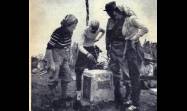El doctor Manuel Sánchez Silveira, colocando el acta oficial de la expedición en la urna que existía en el Pico Turquino. Aparecen también en la foto Jilma Madera, Aníbal T Díaz y Celia Sánchez