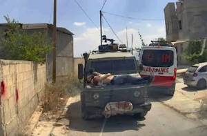 Herido y detenido este joven palestino es llevado sobre el capo de un vehículo militar israelí en Jenin.
