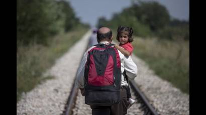 Refugiado sirio llevando a su hija en brazos