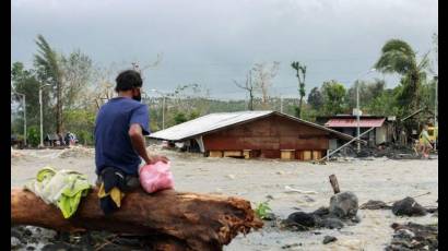 Un hombre observa su casa sepultada por escombros y arena tras las inundaciones repentinas provocadas por el tifón Goni