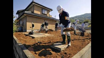 Voluntarios trabajan para descontaminar el suelo de un jardín de casa en la prefectura de Fukushima.