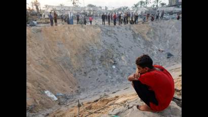 Un niño palestino observa el cráter dejado por los ataques israelíes contra un campamento de tiendas de Al Mawasi