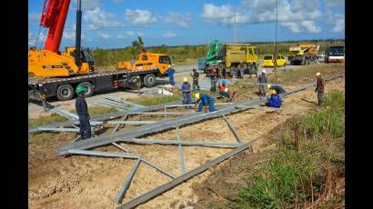 Varias manos solidarias levantan en el kilómetro 32 de la autopista nacional Habana-Pinar del Río, la primera de las seis torres destrozadas por el huracán Rafael