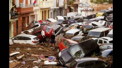 Vehículos apilados en el barro después de ser arrastrados por las inundaciones en Valencia, España