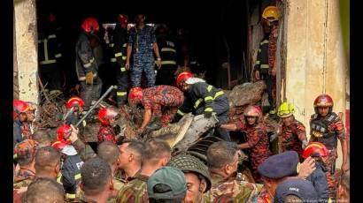 Un cuerpo de rescate y bomberos rastrea entre los restos del avión estrellado en Daca, Bangladés.