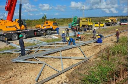 Varias manos solidarias levantan en el kilómetro 32 de la autopista nacional Habana-Pinar del Río, la primera de las seis torres destrozadas por el huracán Rafael