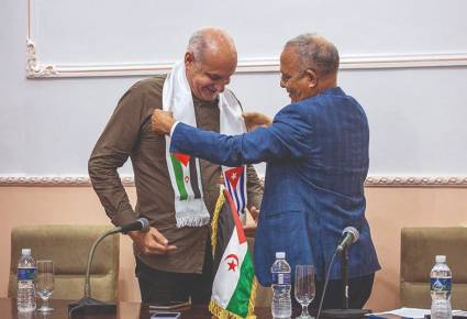 El embajador saharauí en Cuba, Omar Bulsan, coloca la banda con las banderas de la RASD y Cuba a Ricardo Ronquillo, presidente de la UPEC.