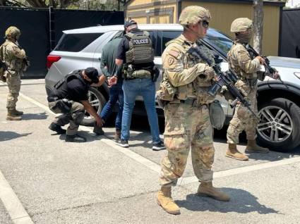 Miembros de la Guardia Nacional custodian a agentes del Servicio de Inmigración y Control de Aduanas