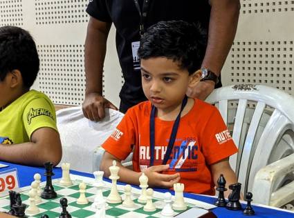 Anish Sarkar usa una pila de sillas para alcanzar el tablero