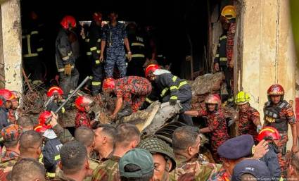 Un cuerpo de rescate y bomberos rastrea entre los restos del avión estrellado en Daca, Bangladés.
