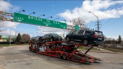 Un camión con vehículos se dispone a cruzar el puente Ambassador desde Canadá a Estados Unidos.